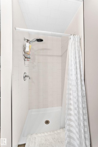White tiled shower enclosure with a white shower pan and a chrome shower fixture - #418 279 Suder Greens Dr Nw, Edmonton, AB 