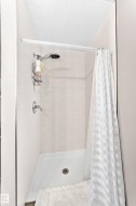 White tiled shower enclosure with a white shower pan and a chrome shower fixture - 