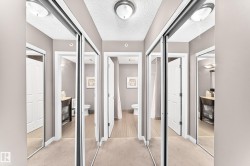 Hallway featuring mirrored sliding closet doors, flush mount lighting, and wood-finish flooring visible through doorways - 