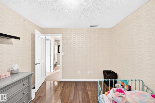 Wood-finish flooring, textured wall covering, and white interior doors - #418 279 Suder Greens Dr Nw, Edmonton, AB 