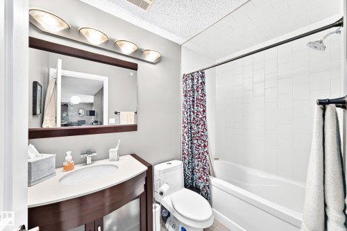 Vanity with integrated sink, white countertop, and dark wood-finish cabinetry - #418 279 Suder Greens Dr Nw, Edmonton, AB 