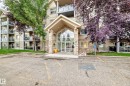 Building exterior featuring a stone-clad entrance, expansive glass doors, and multiple private balconies with glass railings - #418 279 Suder Greens Dr Nw, Edmonton, AB 
