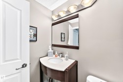 White paneled door with polished hardware, wall-mounted vanity lighting, framed mirror, curved vanity with integrated sink, and light-toned walls - 
