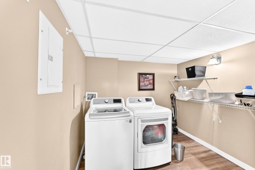 Utility area with wood-finish flooring, wire shelving, and a drop ceiling - #418 279 Suder Greens Dr Nw, Edmonton, AB 
