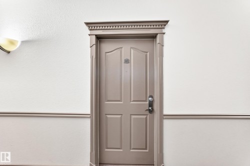 Panel door with decorative molding, wall sconce, and chair rail detailing - #418 279 Suder Greens Dr Nw, Edmonton, AB 