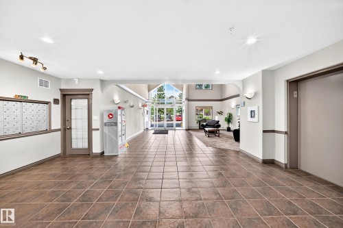Spacious common area featuring tile flooring, a mail center, and an elevator - #418 279 Suder Greens Dr Nw, Edmonton, AB 