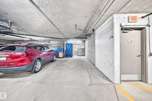 Concrete flooring throughout, exposed ceiling pipes, concrete walls, marked exit door, overhead lighting - #418 279 Suder Greens Dr Nw, Edmonton, AB 