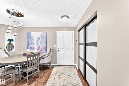 Hardwood-finish flooring, contemporary chandelier, paneled entry door, and sliding closet doors with frosted glass panels - #418 279 Suder Greens Dr Nw, Edmonton, AB 