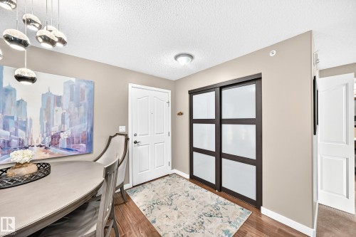 Wood-finish flooring with a white entry door, recessed lighting, and modern sliding closet doors - #418 279 Suder Greens Dr Nw, Edmonton, AB 
