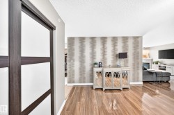 Hardwood-finish flooring throughout, accent wall with patterned wallpaper, and a dark wood-frame sliding door - 