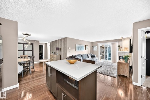 Kitchen island with integrated microwave, wood-finish flooring, recessed lighting, and a sliding glass door - #418 279 Suder Greens Dr Nw, Edmonton, AB 