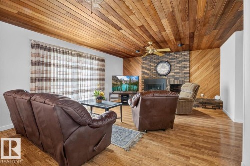 Living area featuring wood-finish flooring and a wood-paneled ceiling - 4027 74 Street Nw, Edmonton, AB - Indoor With Fireplace