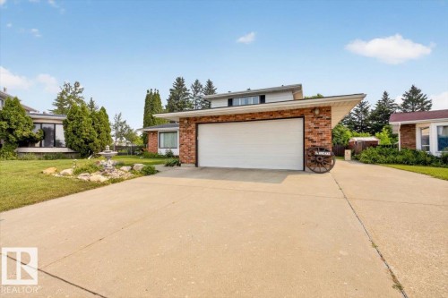 Brick facade residence featuring a two-car garage, concrete driveway, and mature landscaping - 4027 74 Street Nw, Edmonton, AB - Outdoor