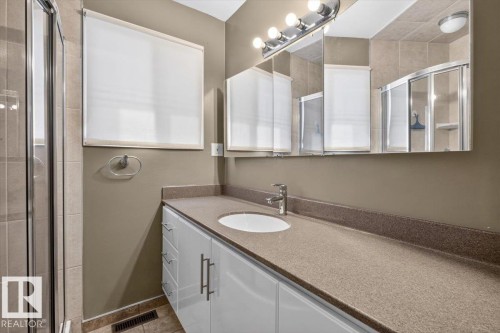 Bathroom featuring a spacious vanity with an integrated sink, ample storage cabinetry, and a wide mirror with overhead lighting - 4027 74 Street Nw, Edmonton, AB - Indoor Photo Showing Bathroom