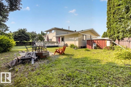 Expansive backyard featuring a built-in fire pit, a wooden deck, and mature perimeter trees - 4027 74 Street Nw, Edmonton, AB - Outdoor With Deck Patio Veranda