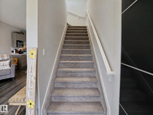 Carpeted staircase with white handrail and a contrasting dark accent wall - 13309 128 Street Nw, Edmonton, AB 