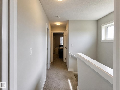 Carpeted hallway with painted walls, recessed lighting, and a window providing natural illumination - 13309 128 Street Nw, Edmonton, AB 