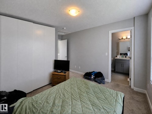 Neutral wall paint, ceiling-mounted light fixture, carpeted flooring, and a door frame leading to a bathroom with a vanity - 13309 128 Street Nw, Edmonton, AB 