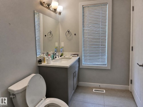 Vanity with an integrated sink, polished chrome faucet, and a wall-mounted mirror - 13309 128 Street Nw, Edmonton, AB 
