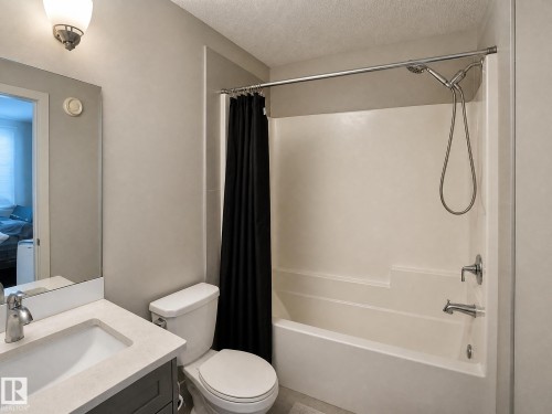Bathroom featuring a vanity with an integrated sink, a toilet, and a bathtub with an overhead shower - 13309 128 Street Nw, Edmonton, AB 