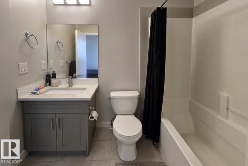 Vanity with gray cabinetry and white countertop, integrated sink, and chrome faucet - 13309 128 Street Nw, Edmonton, AB 
