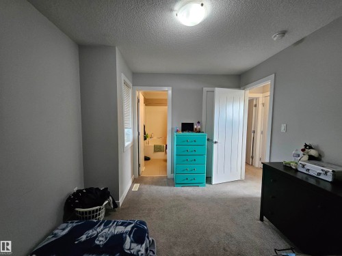 Neutral paint palette with textured ceiling, full-light door with vertical panels, and wall-mounted light fixture - 13309 128 Street Nw, Edmonton, AB 