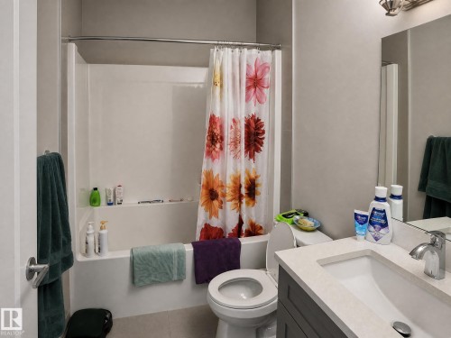 White bath and shower combination with integral shelving, modern vanity with an integrated sink, polished chrome faucet, and integrated lighting fixture - 13309 128 Street Nw, Edmonton, AB 
