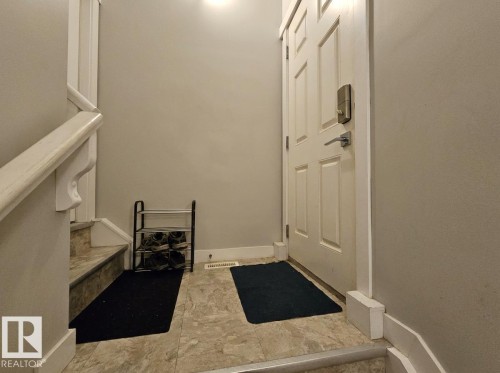 Tiled flooring at entry with painted staircase featuring a white handrail - 13309 128 Street Nw, Edmonton, AB 