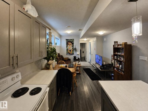 Open-concept living area featuring wood-finish flooring, recessed lighting, and a kitchen with neutral cabinetry and light countertops - 13309 128 Street Nw, Edmonton, AB 