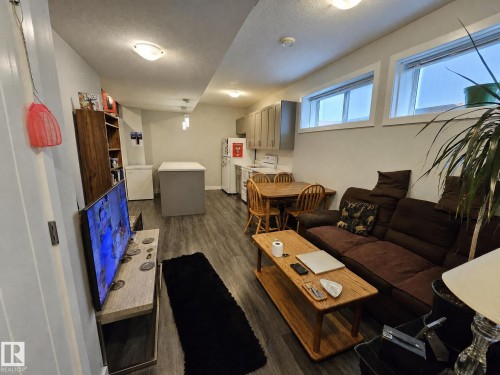 Wood-finish flooring throughout, with a functional kitchen featuring upper cabinetry and a freestanding range - 13309 128 Street Nw, Edmonton, AB 