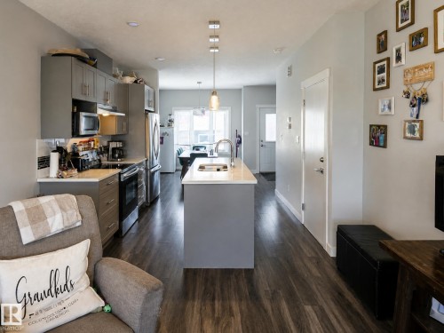 Kitchen featuring grey cabinetry, stainless steel appliances, a center island with sink, and wood-finish flooring - 13309 128 Street Nw, Edmonton, AB 