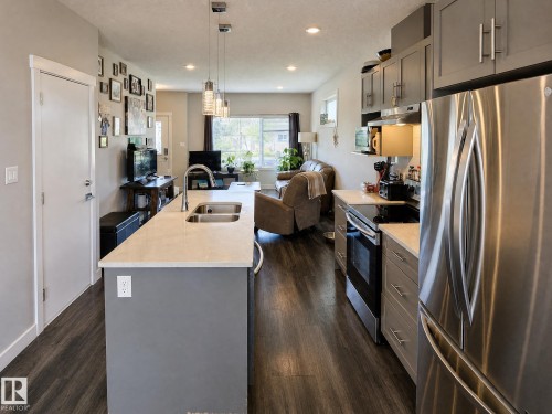 Open-concept living space with dark wood-finish flooring, recessed lighting, and a kitchen island featuring an undermount double-basin sink - 13309 128 Street Nw, Edmonton, AB 