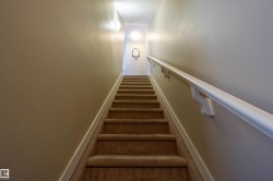 Carpeted stairway featuring a handrail, wall sconce, and recessed lighting - 