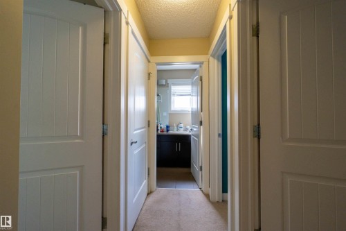 Hallway with carpet flooring and multiple paneled interior doors - #75 8315 180 Av Nw, Edmonton, AB 