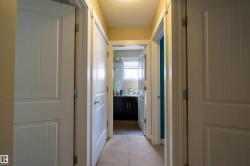 Hallway with carpet flooring and multiple paneled interior doors - 