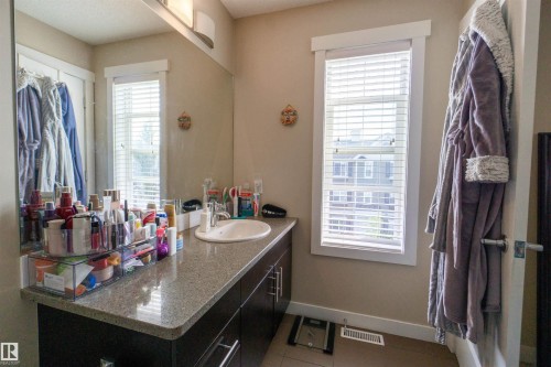 Integrated vanity with an oval basin sink, a stone-finish countertop, and dark wood-finish cabinetry - #75 8315 180 Av Nw, Edmonton, AB 