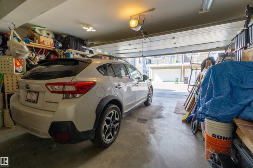 Attached garage with concrete flooring, overhead lighting, and an automatic garage door opener - #75 8315 180 Av Nw, Edmonton, AB 