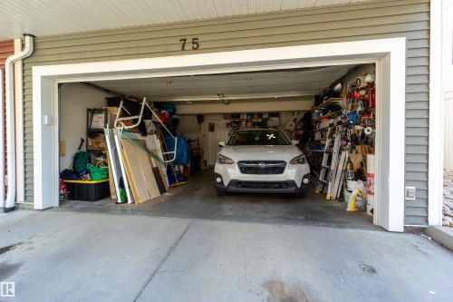 Attached garage with concrete flooring, horizontal siding exterior, and a prominent unit number - #75 8315 180 Av Nw, Edmonton, AB 
