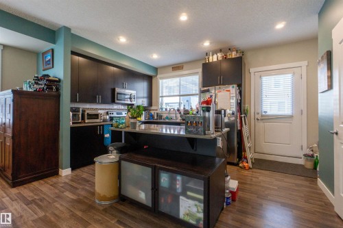 Kitchen with dark wood-finish cabinetry, stainless steel appliances, and a tiled backsplash - #75 8315 180 Av Nw, Edmonton, AB 