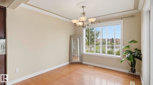 Spacious interior room featuring wood-finish flooring, crown molding, and a built-in chandelier with an ornate ceiling medallion - 6116 53 Avenue, Beaumont, AB - Indoor Photo Showing Other Room