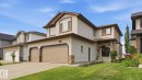 Two-story property featuring light-toned siding, a two-car garage with brown doors, and a covered entry with stone-look accents - 6116 53 Avenue, Beaumont, AB  - Outdoor With Facade 
