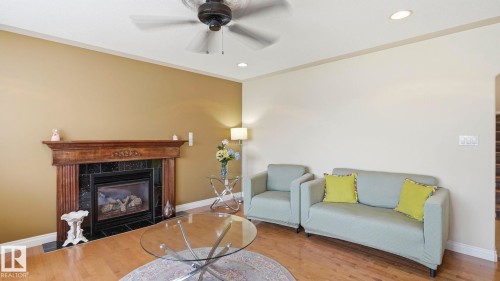 Living area featuring a dark wood fireplace with black tile surround, recessed lighting, and a ceiling fan - 6116 53 Avenue, Beaumont, AB - Indoor Photo Showing Living Room With Fireplace