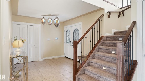 Tiled entryway featuring a decorative three-light chandelier, a white double-door closet, and a front entry door with decorative glass inserts - 6116 53 Avenue, Beaumont, AB - Indoor Photo Showing Other Room