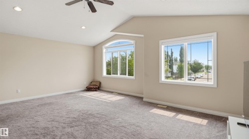 Spacious room featuring vaulted ceilings, recessed lighting, a ceiling fan, and two large windows with decorative grilles - 6116 53 Avenue, Beaumont, AB - Indoor Photo Showing Other Room