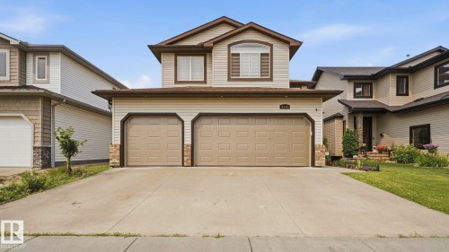 Two-story residential property featuring a two-car garage with panel doors and a concrete driveway - 6116 53 Avenue, Beaumont, AB - Outdoor With Facade