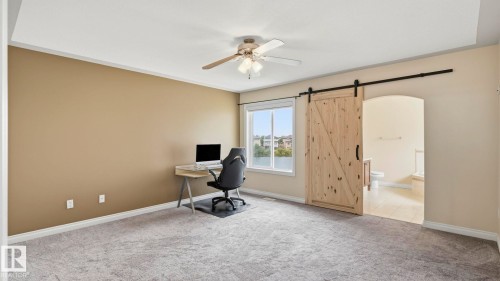 Spacious room with light gray carpeting and a tray ceiling featuring a ceiling fan - 6116 53 Avenue, Beaumont, AB - Indoor
