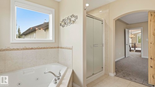 Soaking tub with tiled surround, separate enclosed shower, large window, and arched doorway - 6116 53 Avenue, Beaumont, AB - Indoor Photo Showing Bathroom