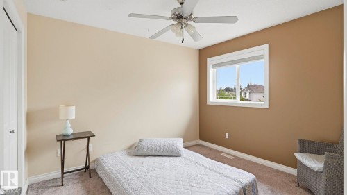 Carpeted room featuring a ceiling fan with integrated lighting, a window with white trim, and a bi-fold closet door - 6116 53 Avenue, Beaumont, AB - Indoor Photo Showing Bedroom