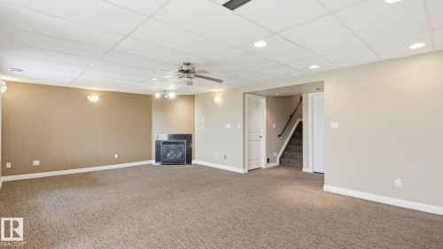Spacious finished room featuring textured carpeting, recessed lighting, and a modern fireplace with a dark stone surround - 6116 53 Avenue, Beaumont, AB - Indoor