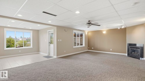 Spacious multi-zone room featuring recessed lighting, a ceiling fan, and a fireplace with a dark tile surround - 6116 53 Avenue, Beaumont, AB - Indoor